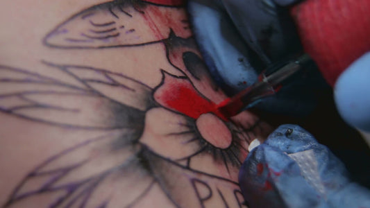 Professional tattoo artist using Relieve spray numbing treatment client comfort